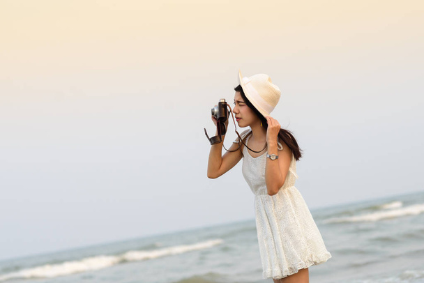Asian woman wearing hat with white dress taking photo on the bea - Fotografie, Obrázek