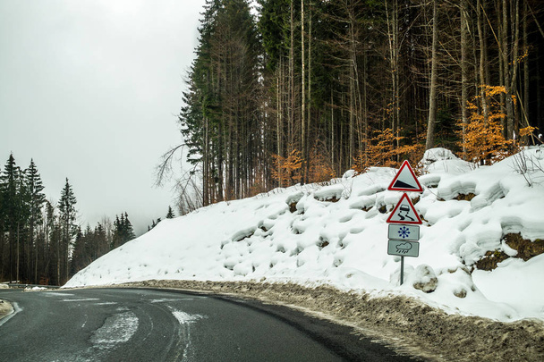 Viaje de invierno en coche a través del paso de montaña. Un giro brusco y señales de advertencia en el camino en las montañas
 - Foto, imagen