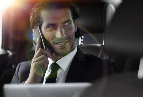 Handsome businessman using mobile phone in car. - Foto, Imagen