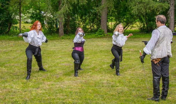 Bernovo/Russia - June 5 2016:The master of fencing and his beautiful students in the clothes of the past era. There is an exhibition of girls with swords in a clearing surrounded by forest. - Foto, Bild