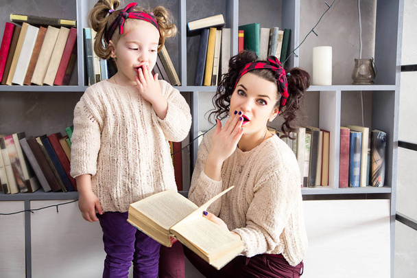 μικρό κορίτσι και τη μάνα με ένα βιβλίο στα χέρια έκπληκτος - Φωτογραφία, εικόνα