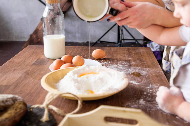 Mom and daughter are cooked together from flour, eggs and milk - Фото, изображение