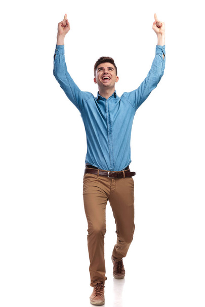 walking casual man celebrting success with hands in the air  - Фото, зображення