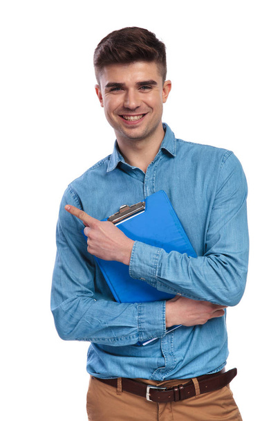 молодий щасливий студент тримає блокнот і вказує пальцем в бік
  - Фото, зображення