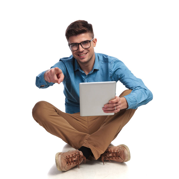 młody człowiek, czytanie na tablet i punkty palca siedząc  - Zdjęcie, obraz