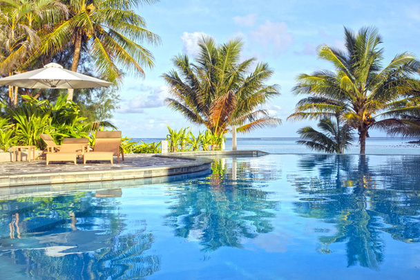 Swimming pool in tropical resort at sunset - Photo, Image