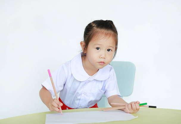 Asian child in school uniform with pencil writing on table isolated on white background. - Fotografie, Obrázek