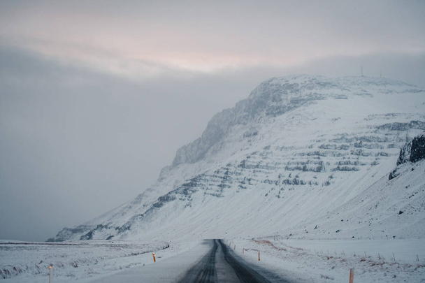 Beautiful View and winter landscape of Iceland's golden circle road during the sunset with the snow-capped mountain as a background and the road asphalt as a foreground. - Fotó, kép