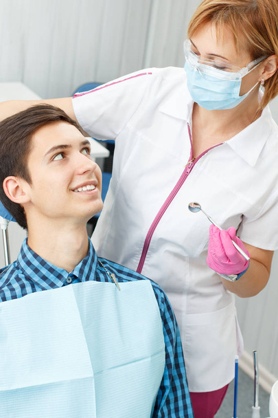 Female dentist and young man in dentist office - Фото, зображення