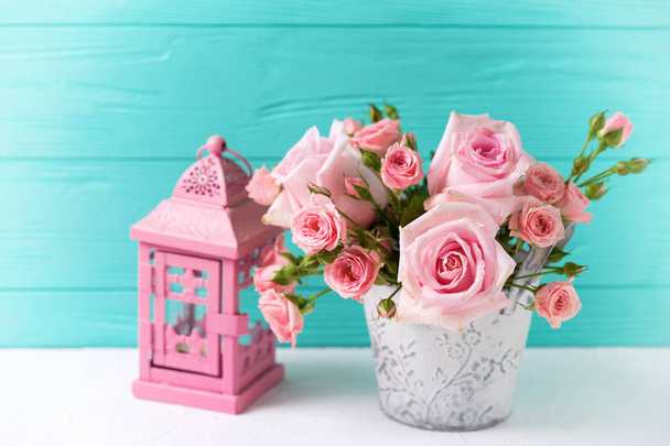 Bunch of tender pink roses flowers and decorative lantern on  white wooden background against turquoise wall. Floral still life.  Selective focus. Place for text.  - Foto, immagini