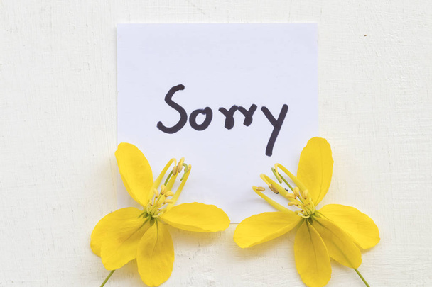  θλιβερό μήνυμα κάρτα επιστολόχαρτο χειρογράφου με κίτρινο λουλούδι σε λευκό φόντο - Φωτογραφία, εικόνα