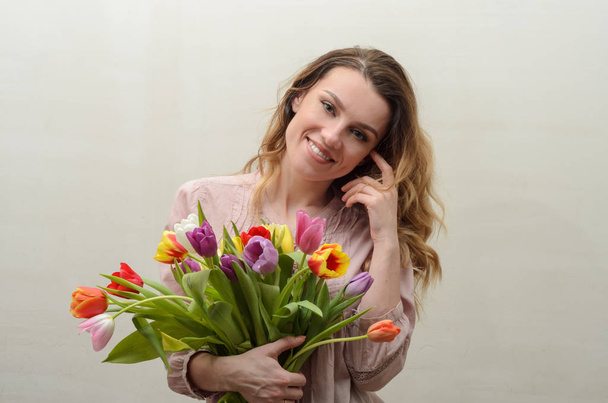 Young charming girl with a bouquet of flowers - multi-colored tulips - 写真・画像