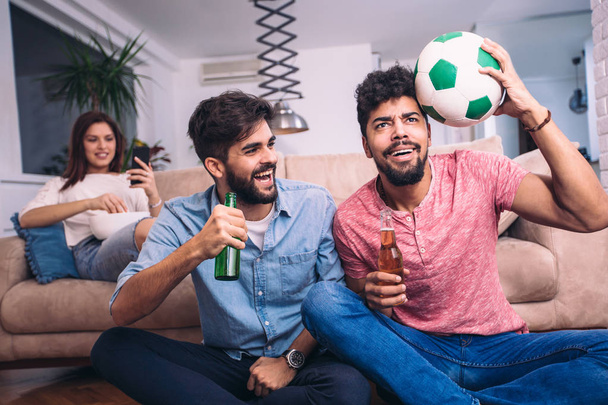 Glückliche Freunde oder Fußballfans, die Fußball im Fernsehen sehen und den Sieg zu Hause feiern. Freundschaft, Sport- und Unterhaltungskonzept. - Foto, Bild