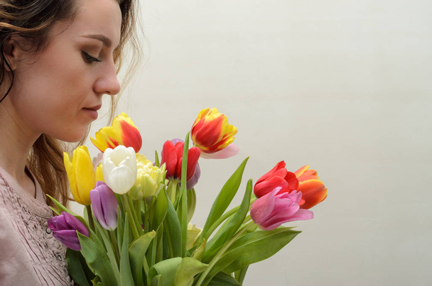 Young charming girl with a bouquet of flowers - multi-colored tulips - Foto, imagen