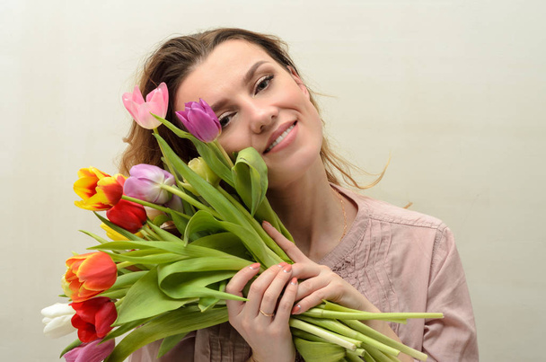 Young charming girl with a bouquet of flowers - multi-colored tulips - Valokuva, kuva