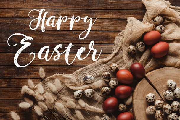 flat lay with easter eggs and ears on cross section of tree trunk and gauze on wood background with Happy Easter inscription - Foto, Imagem