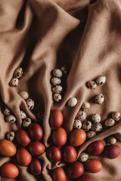 food composition with easter chicken eggs and quail eggs on linen tablecloth - Foto, afbeelding