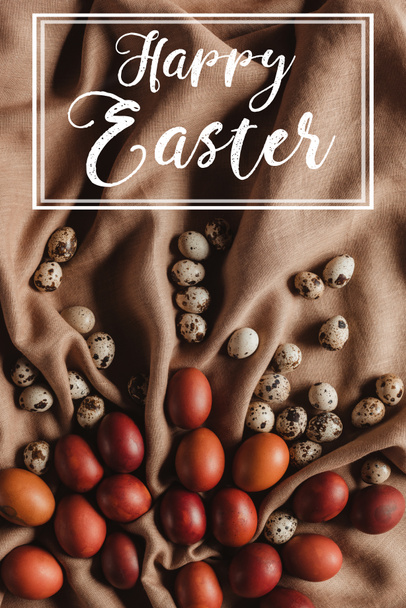 vista superior de huevos pintados de Pascua y huevos de codorniz en mantel de lino con inscripción Feliz Pascua
 - Foto, imagen