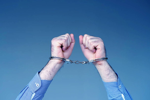 Criminal hands locked in handcuffs. Close-up view - Photo, Image