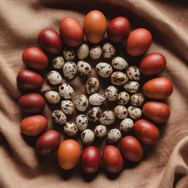 top view of easter quail eggs in circle of chicken eggs on linen tablecloth - Photo, image