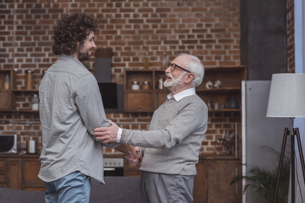 happy adult son and senior father shaking hands at home - Fotoğraf, Görsel