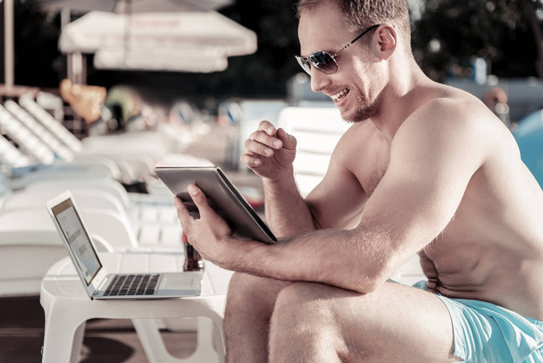Radiant guy grinning broadly while working and sunbathing outdoors - Foto, afbeelding