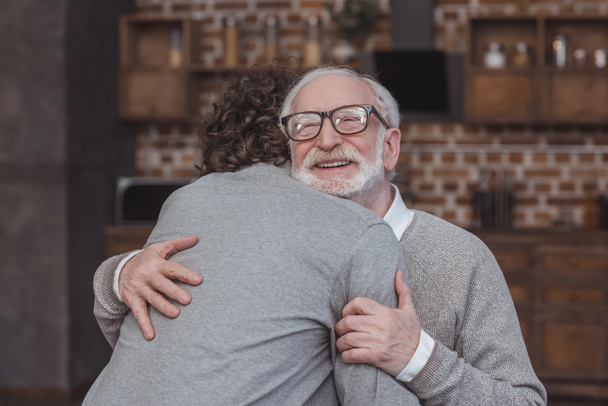 happy adult son and senior father hugging at home - Fotoğraf, Görsel