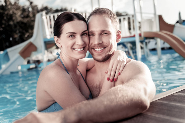 Loving millennial couple embracing in swimming pool - Photo, image
