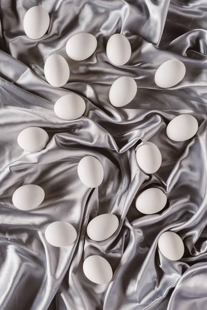 top view of white chicken eggs on silver tablecloth - Foto, afbeelding