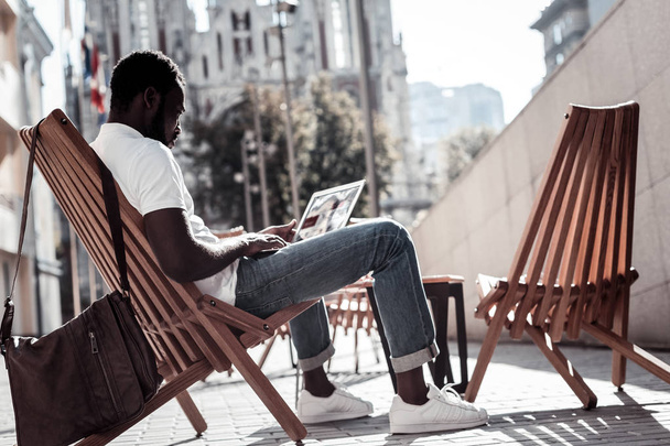 Serious millennial guy working on laptop outdoors - 写真・画像