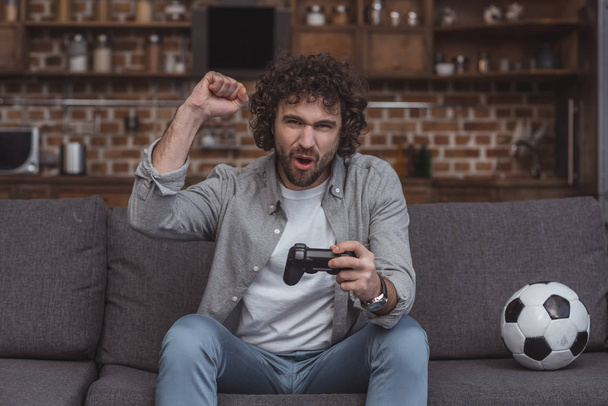 hombre guapo mostrando sí signo mientras juega videojuego en casa
 - Foto, Imagen