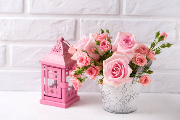 Mazzo di teneri fiori di rose rosa e lanterna rosa decorativa contro il muro di mattoni bianchi. Natura morta floreale. Concentrazione selettiva. Luogo ffor testo
.  - Foto, immagini
