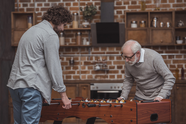adult son and senior father playing table football at home - Valokuva, kuva