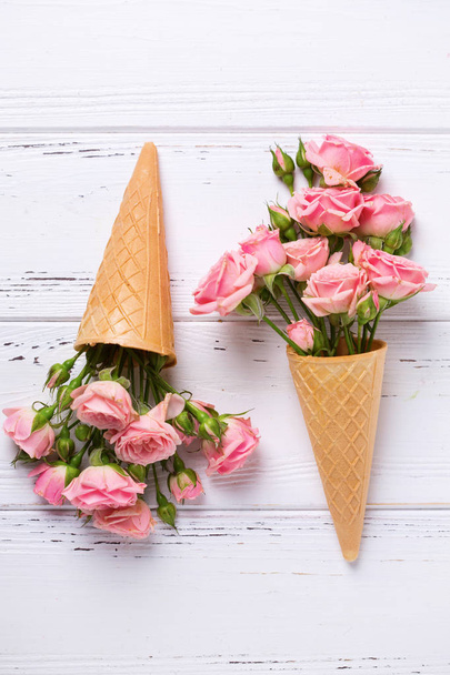 Fresh  pink roses flowers in waffle cones on  white wooden background. Top view. Place for text. - Foto, Imagem