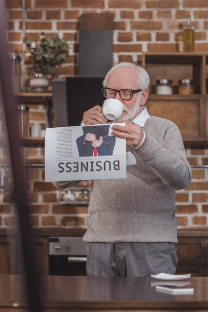 handsome grey hair man drinking coffee and reading business newspaper at home - Zdjęcie, obraz
