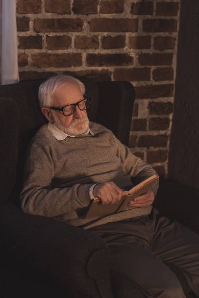 beau livre de lecture homme cheveux gris dans le fauteuil à la maison
 - Photo, image