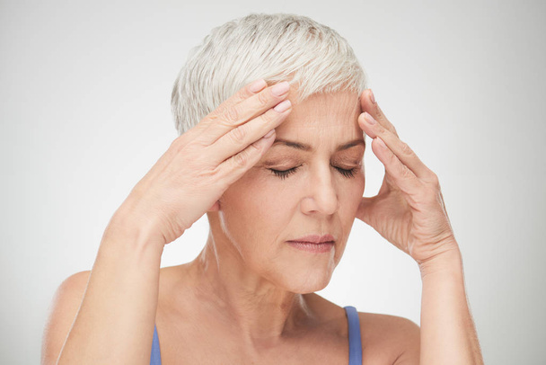 Kopfschuss einer Seniorin mit Kopfschmerzen. Hände auf dem Kopf, Augen c - Foto, Bild