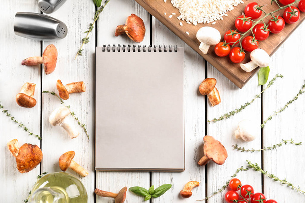 Notebook and ingredients for risotto with mushrooms on wooden background - Фото, изображение