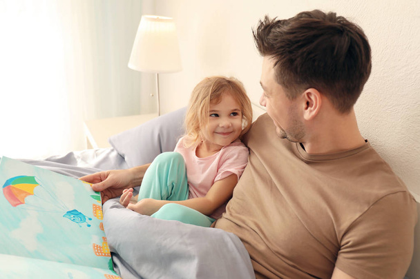 Father with little daughter reading bedtime story at home - Foto, imagen