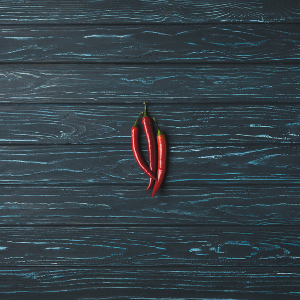 top view of three chili peppers on wooden table - Photo, Image