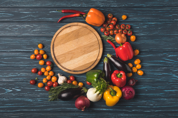 top view of ripe organic vegetables around wooden board on surface - Foto, Bild