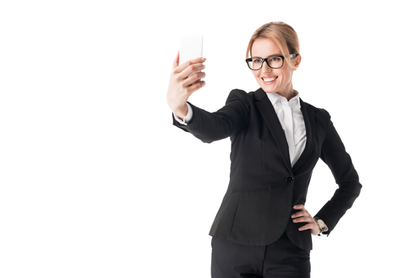 Smiling businesswoman in glasses taking selfie isolated on white - Foto, Imagen