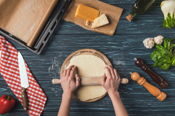 cropped image of woman rolling dough for pizza with rolling pin - Zdjęcie, obraz