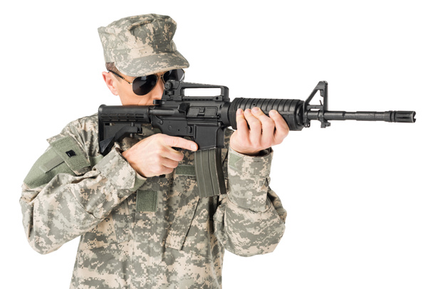 Knappe leger soldaat dragen van uniform gericht met pistool geïsoleerd op wit - Foto, afbeelding