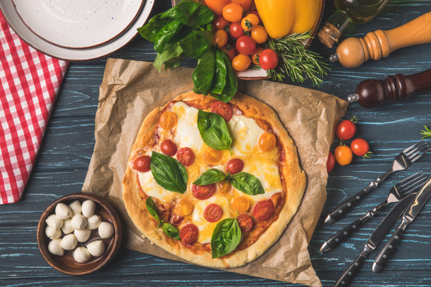 top view of delicious tasty pizza with cherry tomatoes and basil on table - Photo, Image