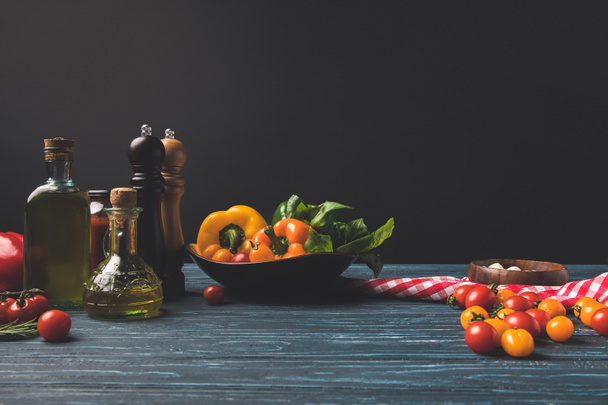 vegetables and oils on wooden table in kitchen isolated on black - Foto, Imagen