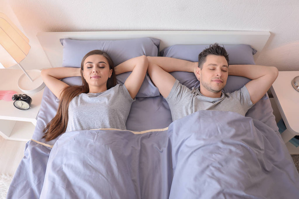 Jeune couple dormant au lit à la maison. Heure du coucher en famille
 - Photo, image