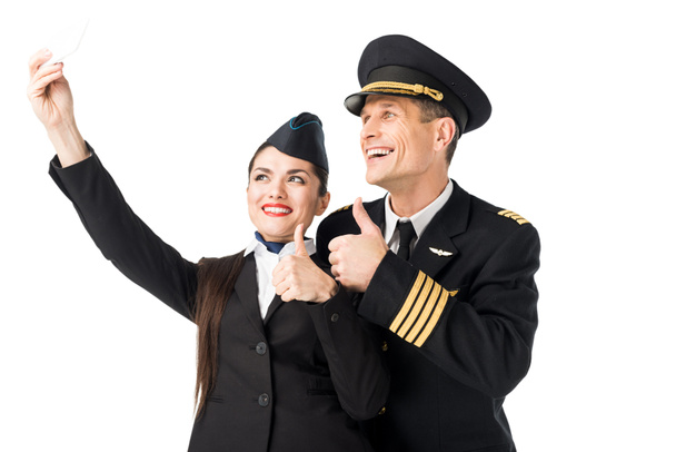 Χαμογελώντας αεροσυνοδός και πιλοτικά λαμβάνοντας αυτοπορτρέτα απομονωθεί σε λευκό - Φωτογραφία, εικόνα