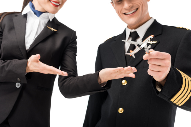 Lachende stewardess en piloot bedrijf speelgoed vliegtuig geïsoleerd op wit - Foto, afbeelding