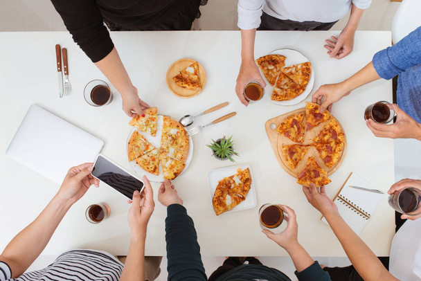 Концепция обеда и людей. Счастливая деловая команда ест пиццу в офисе, вид сверху
 - Фото, изображение